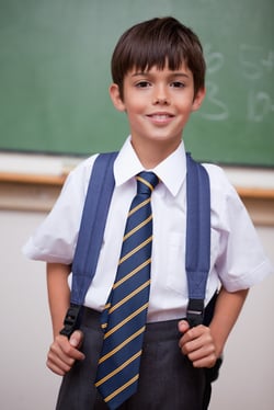Portrait of a smiling schoolboy with a backpack in a classroom